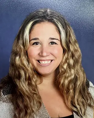 Portrait of a smiling woman with long wavy hair against a blue backdrop.